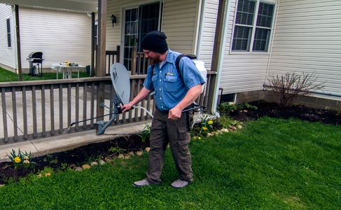 Licensed pest control technician, Jeremy Bannister completing a maintenance service on a residential home perimeter in Erie, PA to exterminate spiders, ants, centipedes.